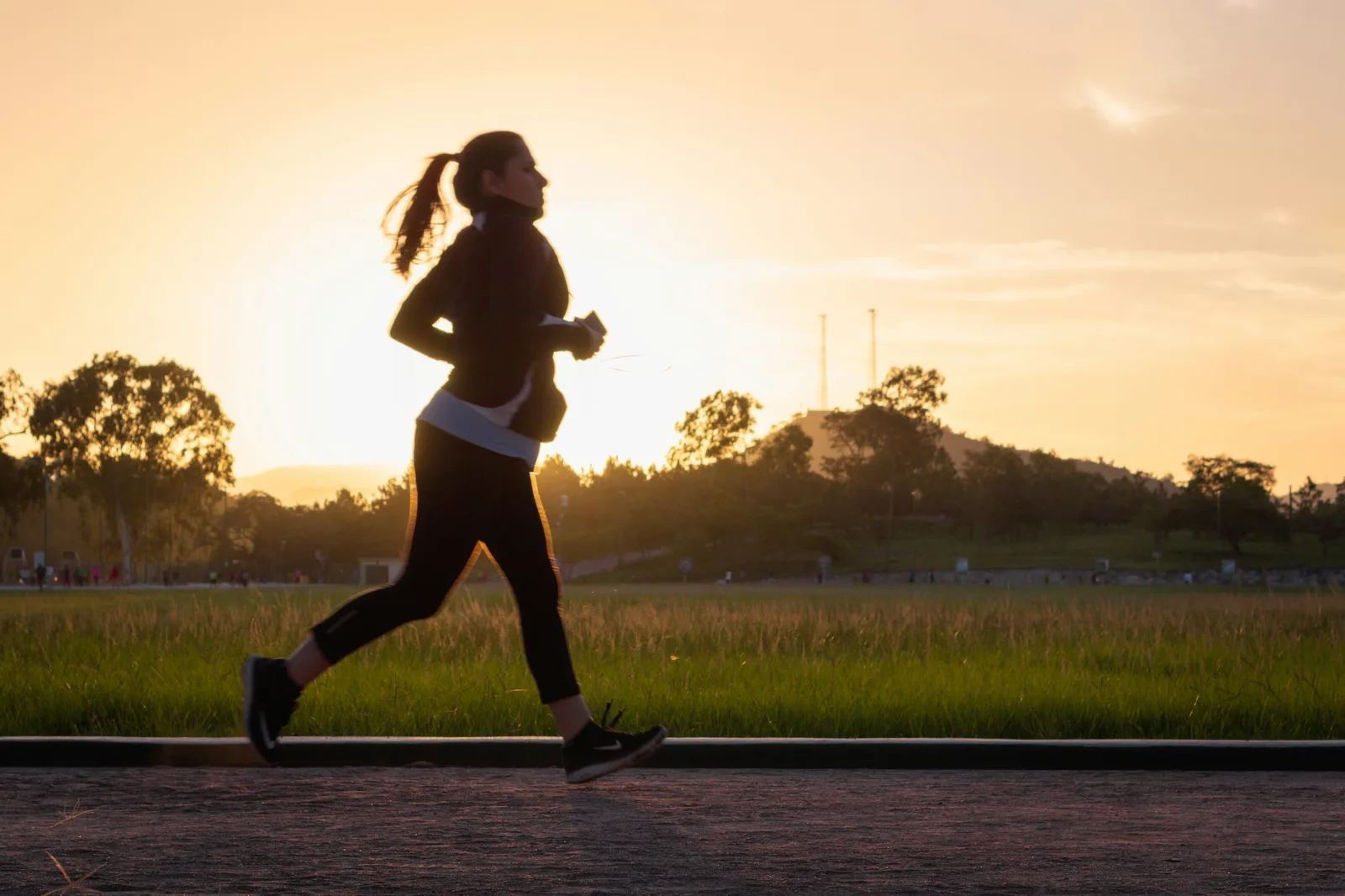 Woman running at sunrise — dynamic fitness hero image
